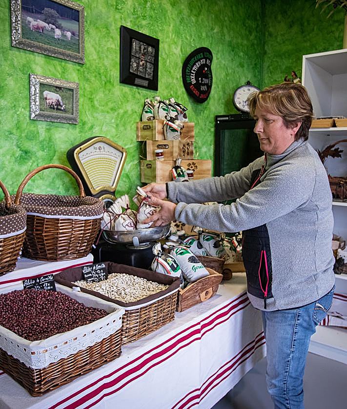 Imagen secundaria 2 - la familia al completo, ante la casa, con los perros Jai y Balto. En las otras fotos, Fermín bromea con Jai, el pastor vasco, que se ha subido a la rueda del tractor, y Jacqueline en la tienda de Nanike. 