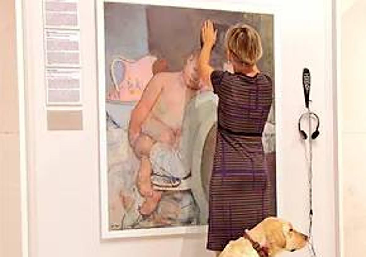 Una mujer con dificultades de visión examina una obra de arte.