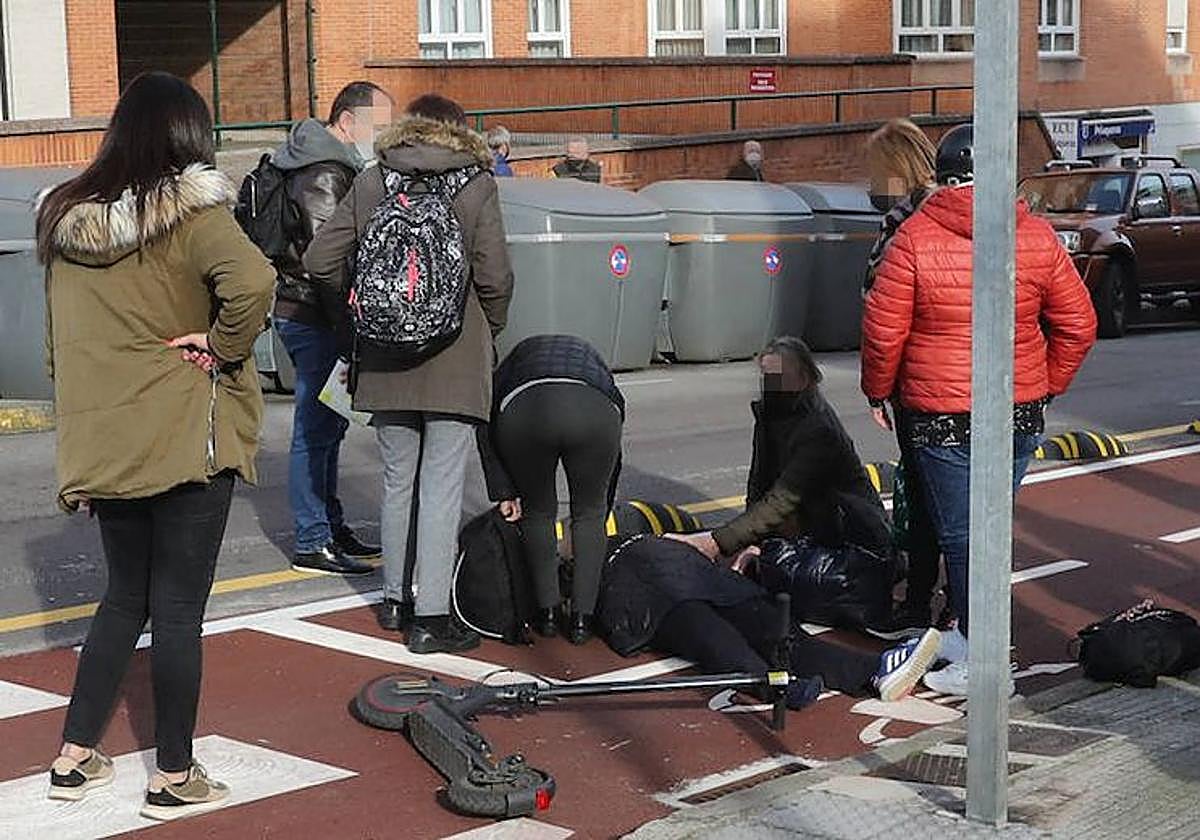 Unos viandantes atienden a una persona que se ha caído de un patinete.