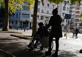 Una mujer y su cuidadora pasean por el parque de Doña Casilda de Bilbao.