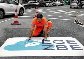 Operarios dan los últimos retoques al logo que avisa, antes de entrar en la Gran Vía desde el Sagrado Corazón, de que se accede a la zona de bajas emisiones.