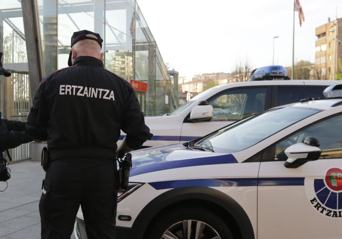 Un agente autonómico junto a dos vehículos policiales junto al metro en Algorta.