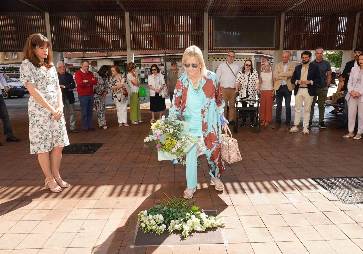 Una sobrina de Eugenio Lázaro coloca un ramo de flores sobre la placa.