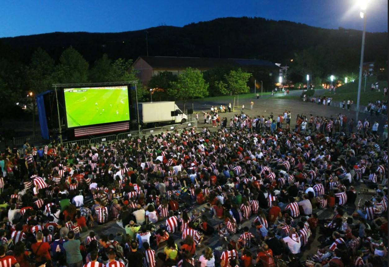 Aficionados del Athletic presencian un partido en una pantalla gigante.