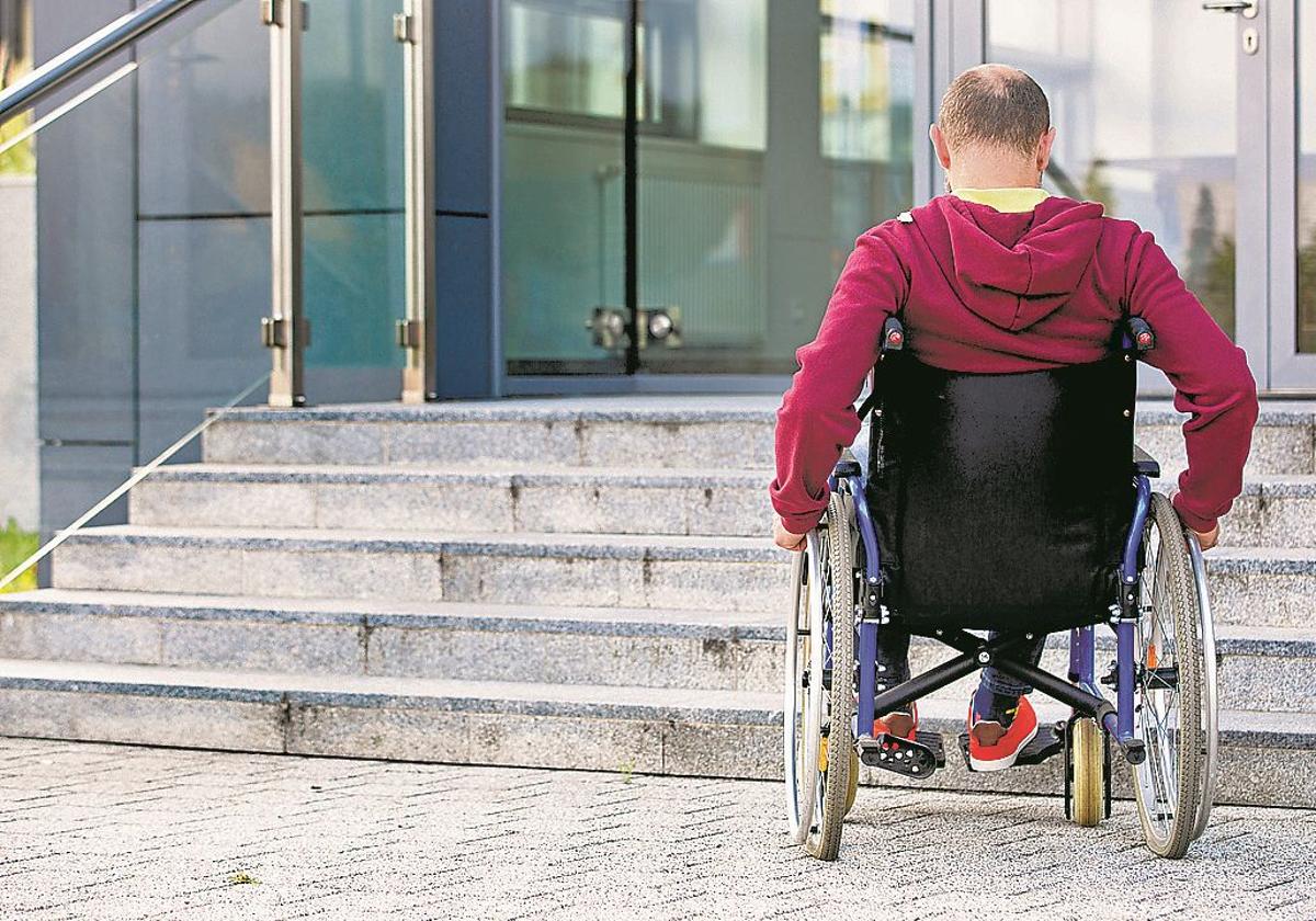 Un hombre en silla de ruedas trata de acceder a un edificio público.