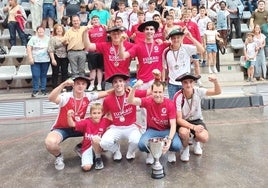 Los integrantes del club de pelota a mano de Markina con los trofeos y sus seguidores detrás.