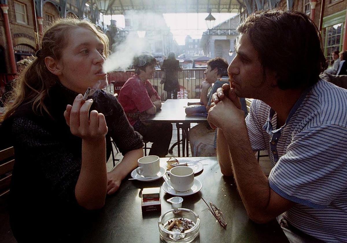 Dos jóvenes fuman en la terraza de una cafetería.