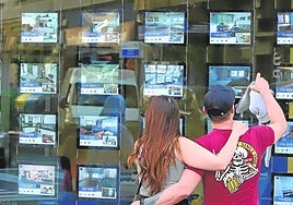 Una pareja observa los anuncios de ventas de viviendas de una inmobiliaria.