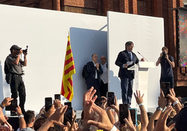 Imagen del escenario en el que se ve a Gonzalo Boye, vestido con camisa blanca, esperando a que Puigdemont finalice su discurso y ayudarle a huir.