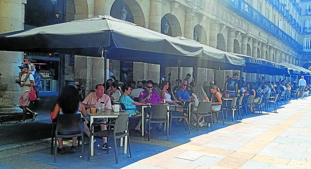 En busca de la sombra en la plaza Nueva. Terrazas llenas en el Casco Viejo con turistas copando las mesas para degustar la gastronomía vasca. Pero eso sí, a la sombra.