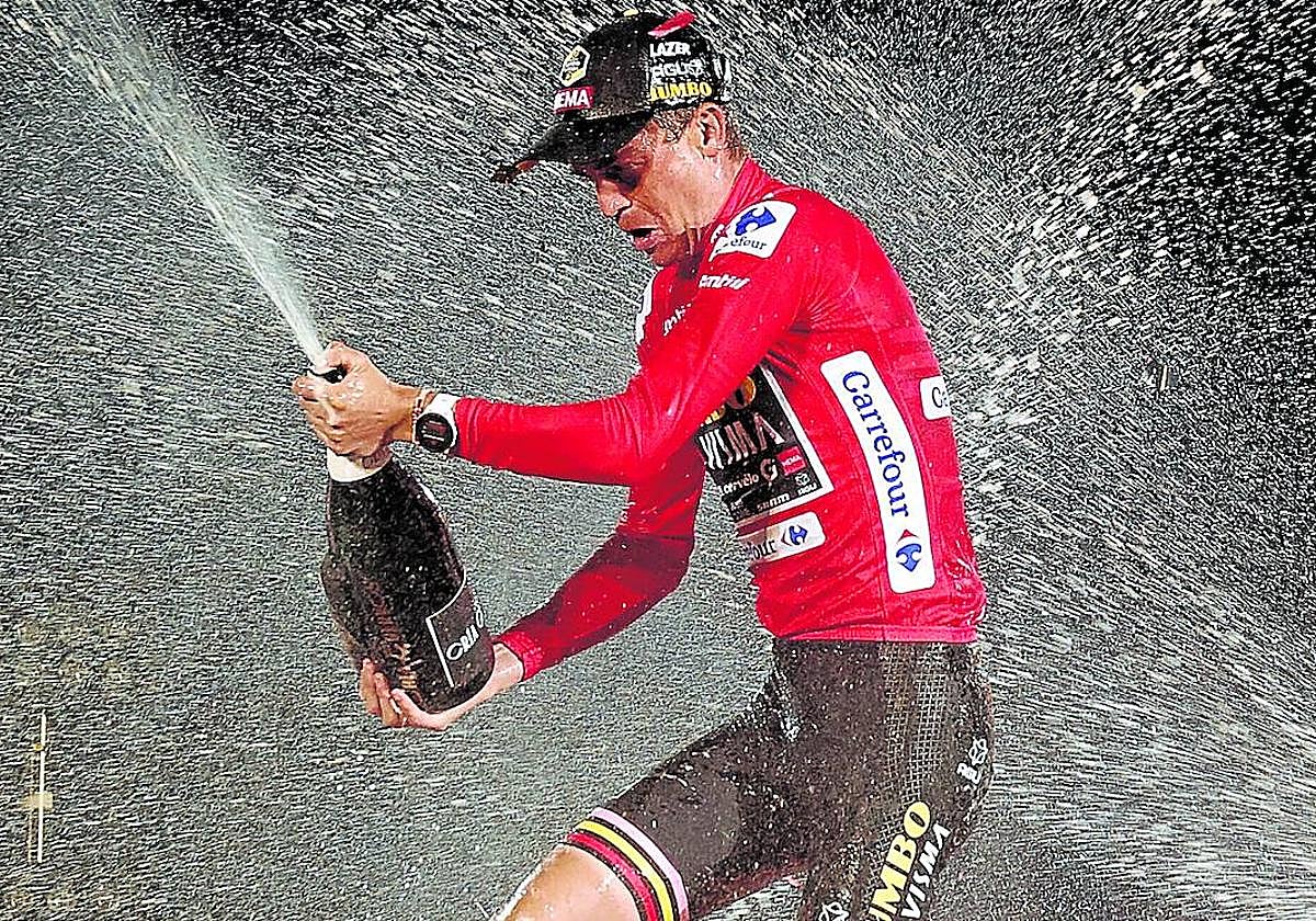 Sepp Kuss descorcha la botella de cava en el podio como campeón de la Vuelta 2023.