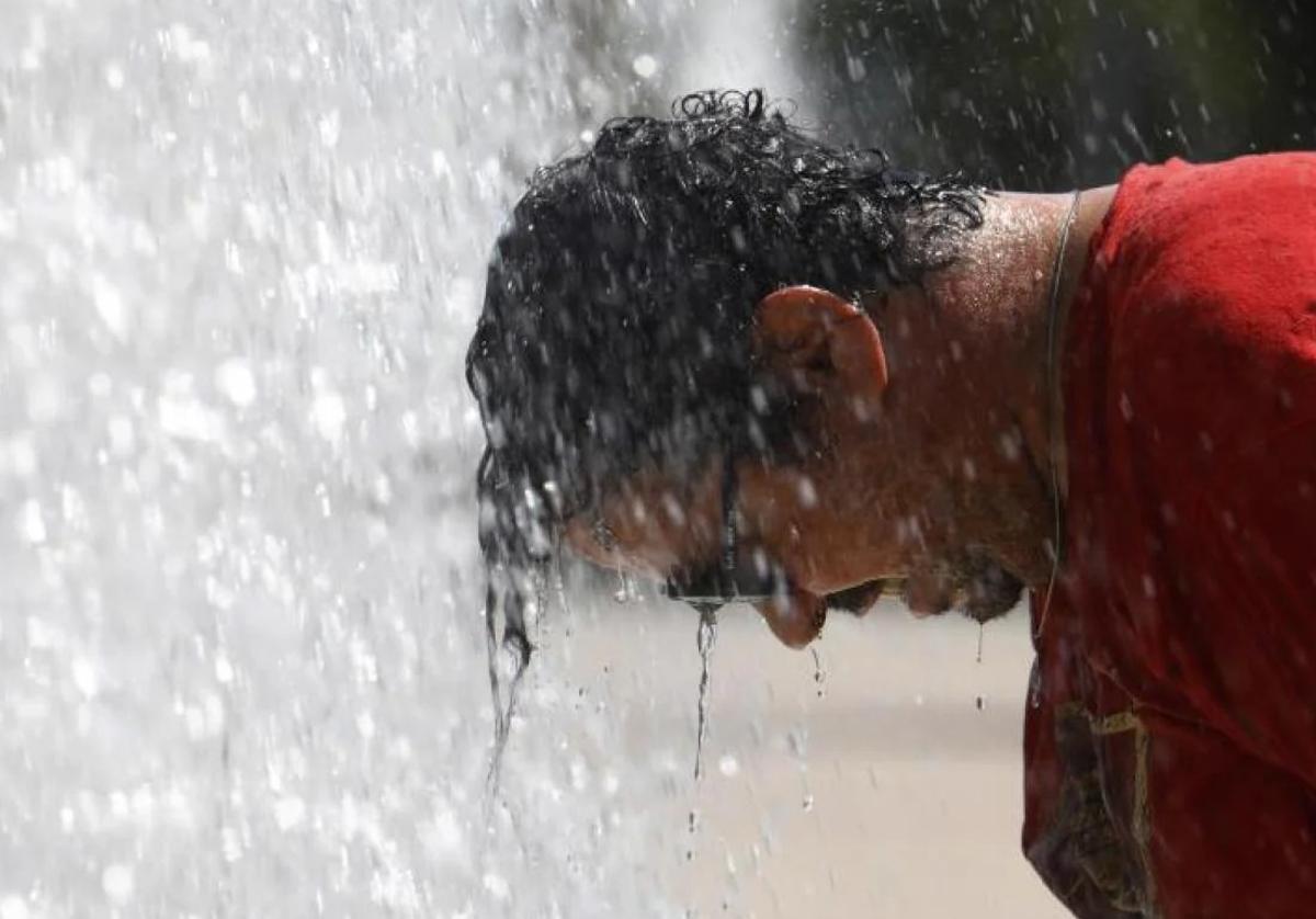 Un hombre se refresca en una fuente de Córdoba.