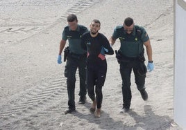 Dos guardias civiles con uno de los inmigrantes llegados este lunes a las playas de Ceuta.