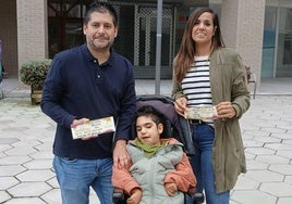 Iris Infante e Iván Corredor muestran las participaciones de la lotería de Navidad junto al pequeño Markel, de 10 años.