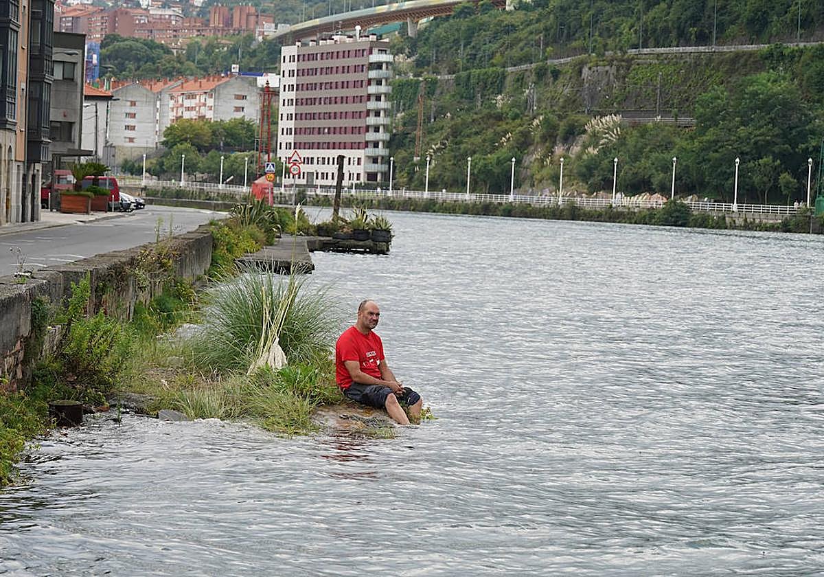 Un hombre se remoja los pies en la ría.