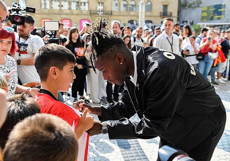 Nico Williams firma una camiseta a un chaval en el exterior de los cines Príncipe.