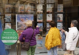 Unas mujeres observan el escaparate de una agencia con ofertas de viajes del Imserso.