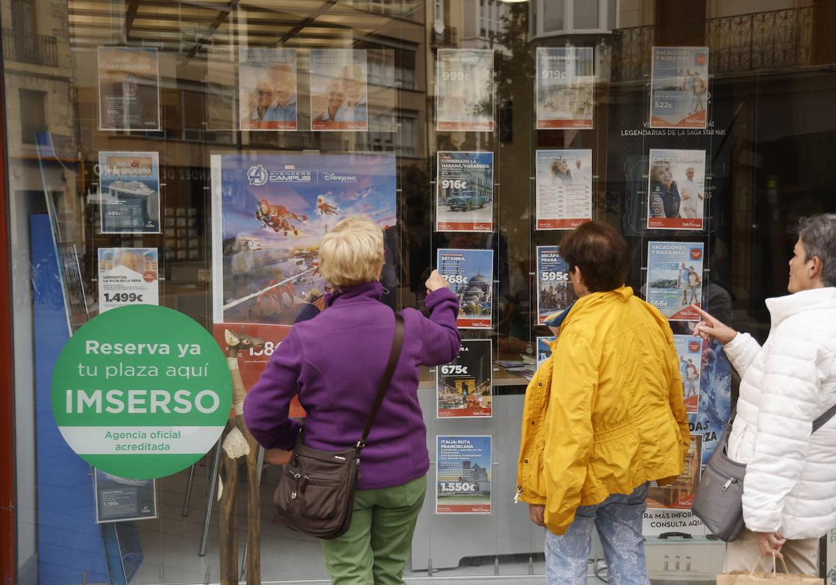 Unas mujeres observan el escaparate de una agencia con ofertas de viajes del Imserso.