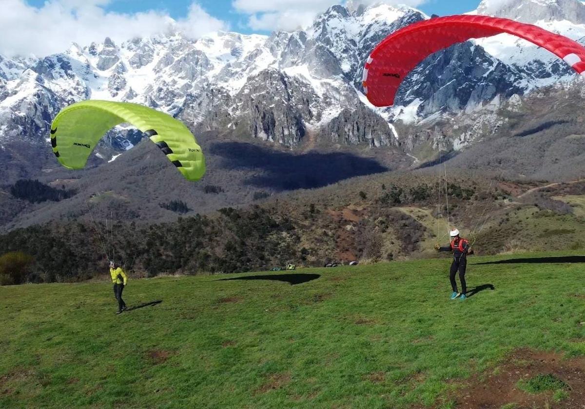 Foto de dos parapentistas con Picos de Europa de fondo.