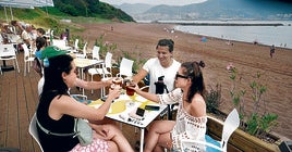Un grupo de chavales toman un refresco en el local hostelero que está en la playa de Arrigunaga en Getxo.