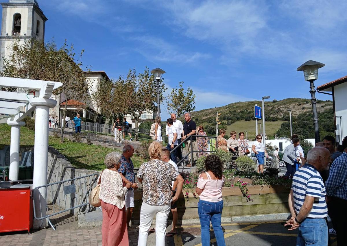 Imagen secundaria 1 - Bisi Fernández, posa sonriente con su nieto, Endika, tras izar la bandera de su pueblo, después de que los vecinos descendieran de la tradicional misa hasta la plaza del Ayuntamiento, donde ha tenido lugar el acto principal de la jornada.