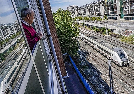 Un hombre observa desde su ventana un tren que abandona la estación de la calle Dato.