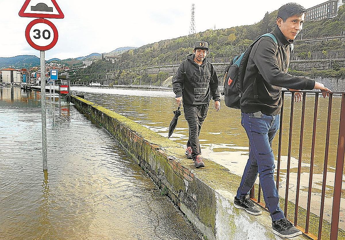 Dos personas caminan por el muro que separa Zorrozaurre de la ría para evitar la zona que cubrió las mareas vivas.
