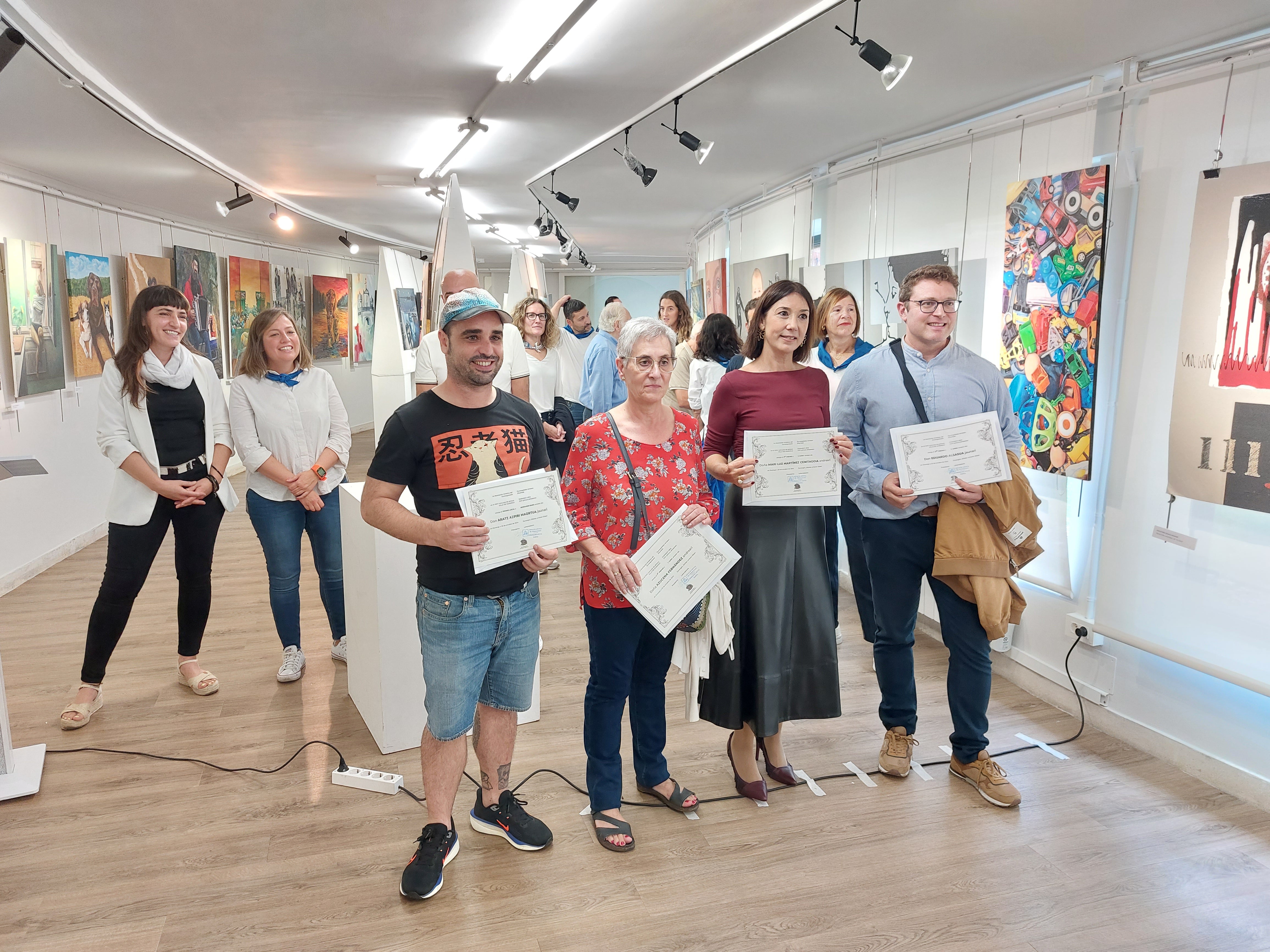 Imagen principal - Foto de familia de los premiados y la primera, Azucena Fernández y el artista local, Aratz Azpiri.