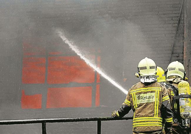 Los bomberos dirigen el chorro de agua hacia una de las ventanas.