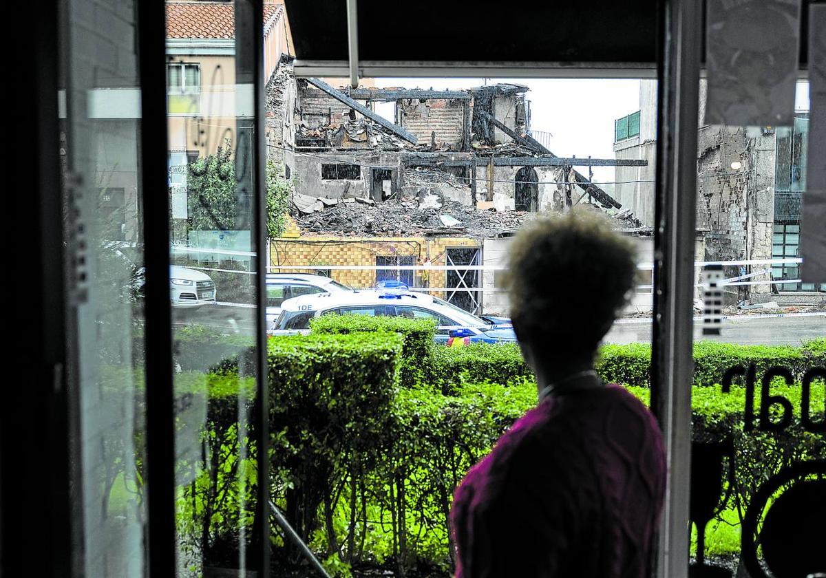 La camarera de una cafetería que se encuentra frente al edificio derrumbado observa los escombros que quedaron tras la explosión.