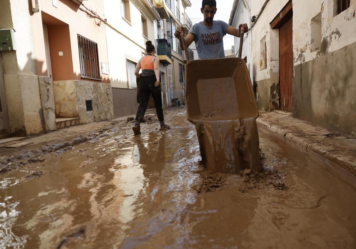 Un joven retira lodo acumulado en el interior de una vivienda en la localidad valenciana de Chiva.