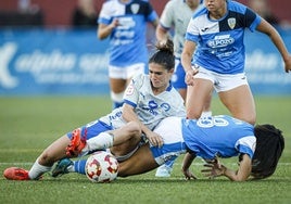 Una jugadora albiazul trata de ganar un balón desde el suelo.