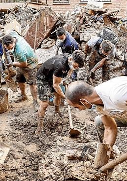 Imagen - Incansables. Varias personas retiran el lodo acumulado en una calle de la localidad valenciana de Paiporta.