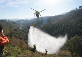 El helicóptero descarga con gran precisión ante la atenta mirada de los Bomberos y agentes forestales.