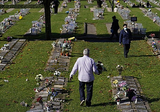 Un hombre se dispone a depositar un ramo de flores en el cementerio de Derio.