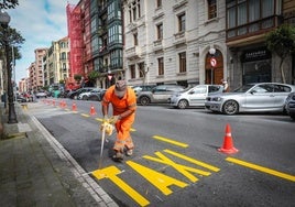 Un operario pinta una parada de taxis en una calle de Bilbao.