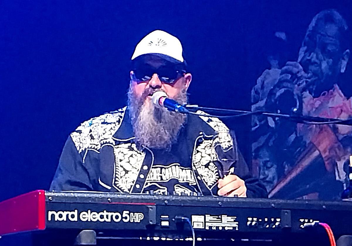 El Reverendo con barba zz top y copa de vino.