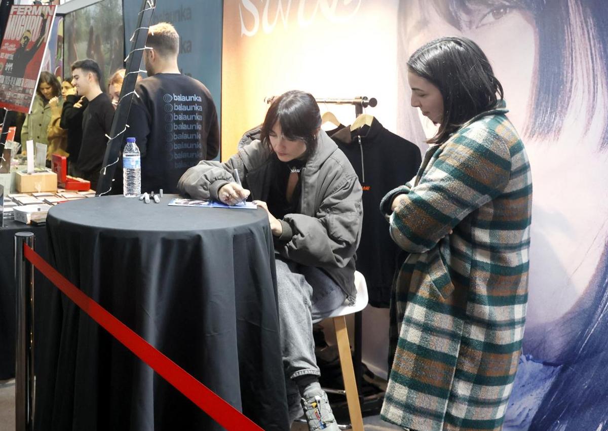 Imagen secundaria 1 - El cantante y guitarra de ETS, Iñigo Etxezarreta, charla con unas fans. Y Josune Arakistain y Aiora Renteria firman sus trabajos a unas seguidoras. 