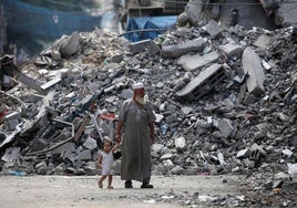 Un hombre camina con su nieta entre las ruinas de Gaza City.