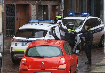 Agentes locales introducen a uno de los okupas en un coche patrulla.