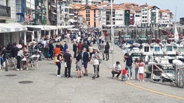 Vecinos de Lekeitio pasean por el muelle en una jornada soleada.