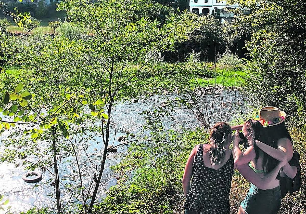 Un grupo de jóvenes observa el Nervión a su paso por Arrankudiaga, con neumáticos y restos de basura.
