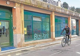 Un ciclista observa el interior del local municipal adaptado como aparcamiento de bicicletas, mientras circula por el bidegorri.