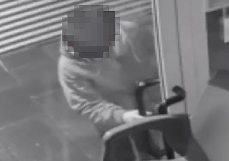 El asaltante intenta levantar la persiana de un local. En esta ocasión, no lo logró.