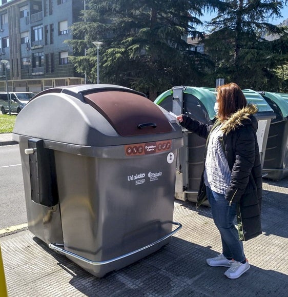 Una mujer acerca la tarjeta que abre la tapa del contenedor marrón.