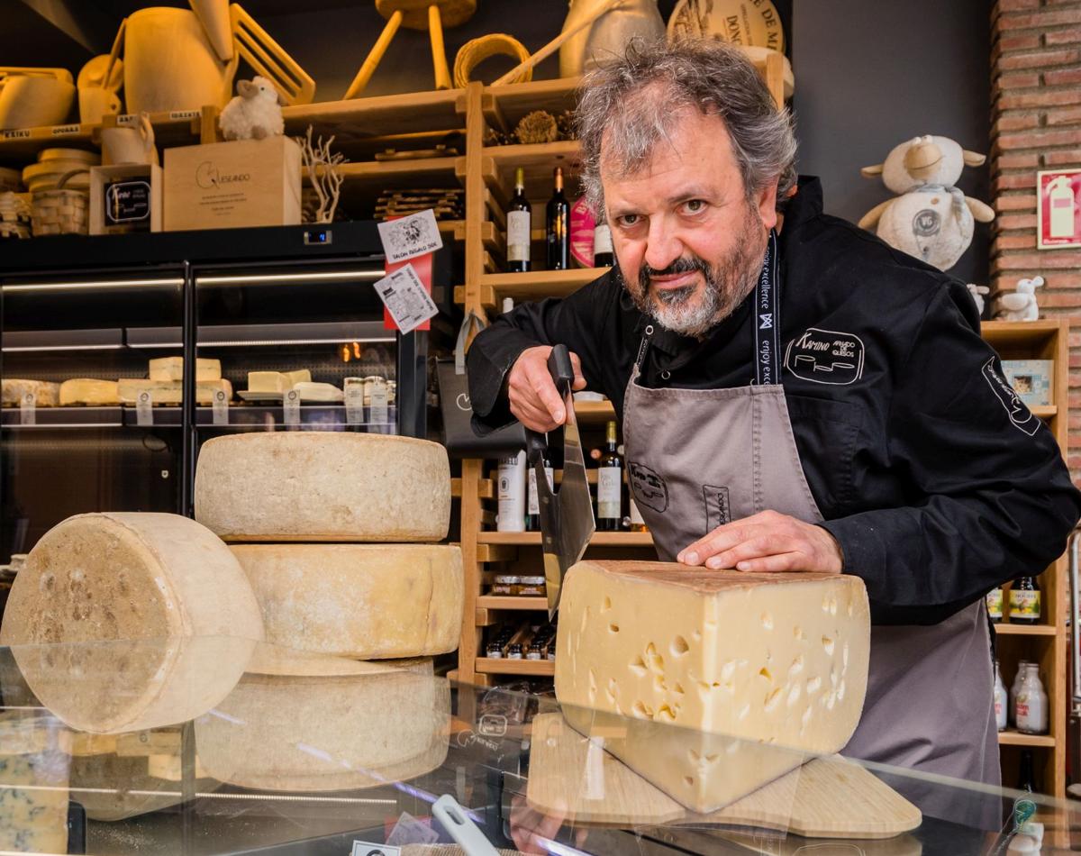Andoni Vigalondo Ochoa de Chinchetru (56) en Queseando junto a quesos Kerroa de 10 kilos que afina en casa y cortando con una pala una porción del gigante suizo Emmental.