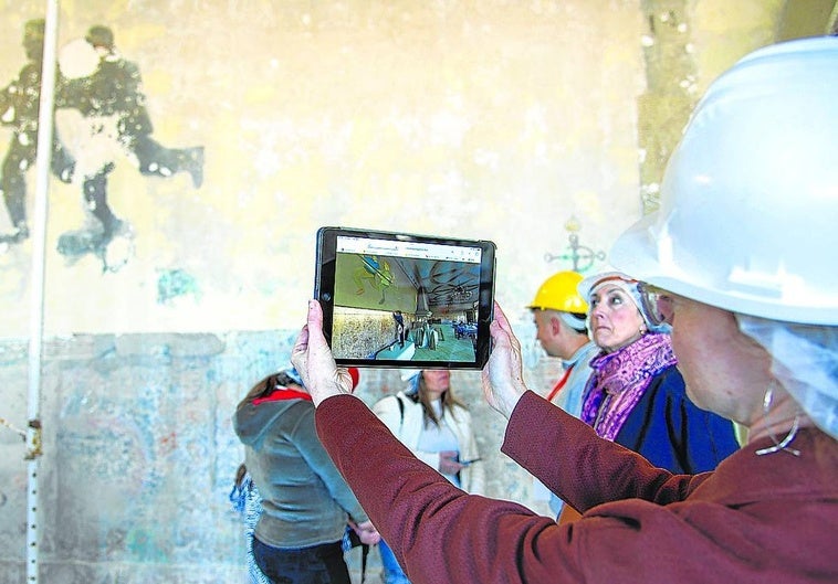 La directora de la Fundación Punta Begoña, María Peraita, muestra a través de una tablet cómo era el salón a comienzos del siglo XX.