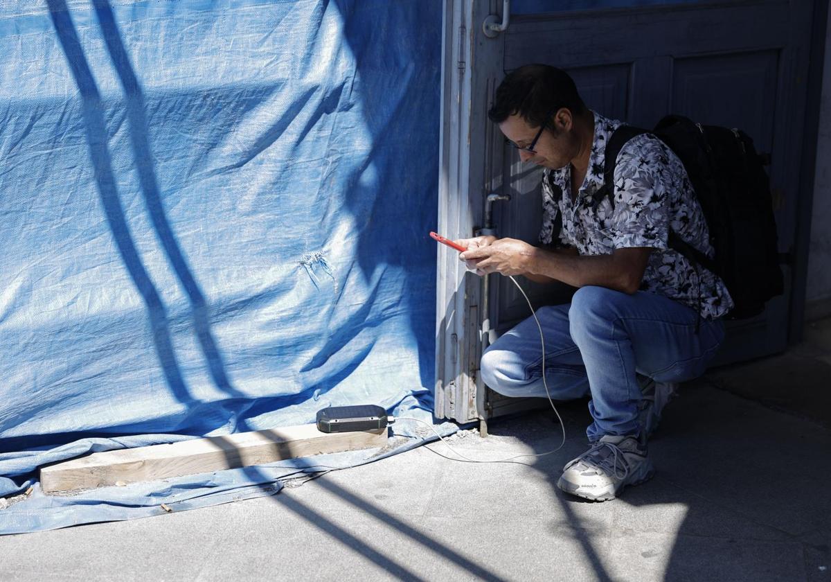 Un joven trata de cargar su móvil con una batería solar.