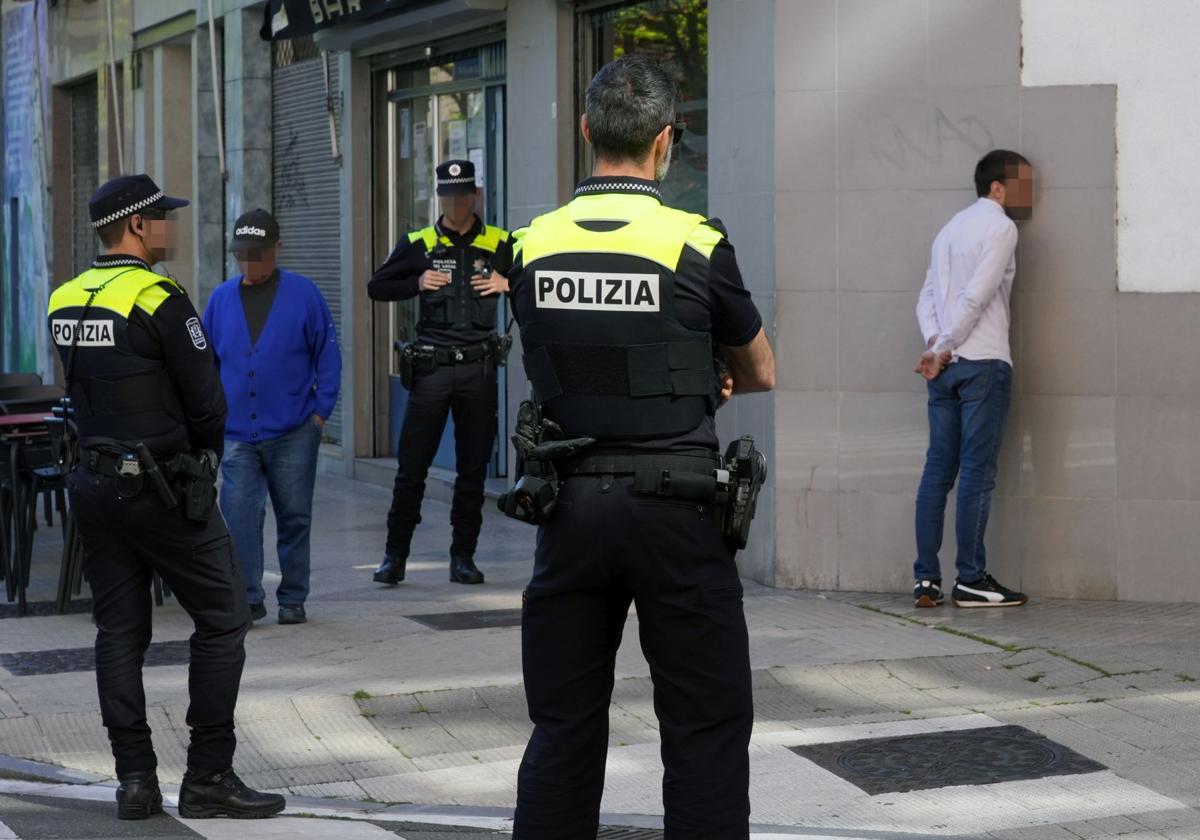 Policías locales custodian a uno de los sospechosos en una calle del barrio de Aranbizkarra.