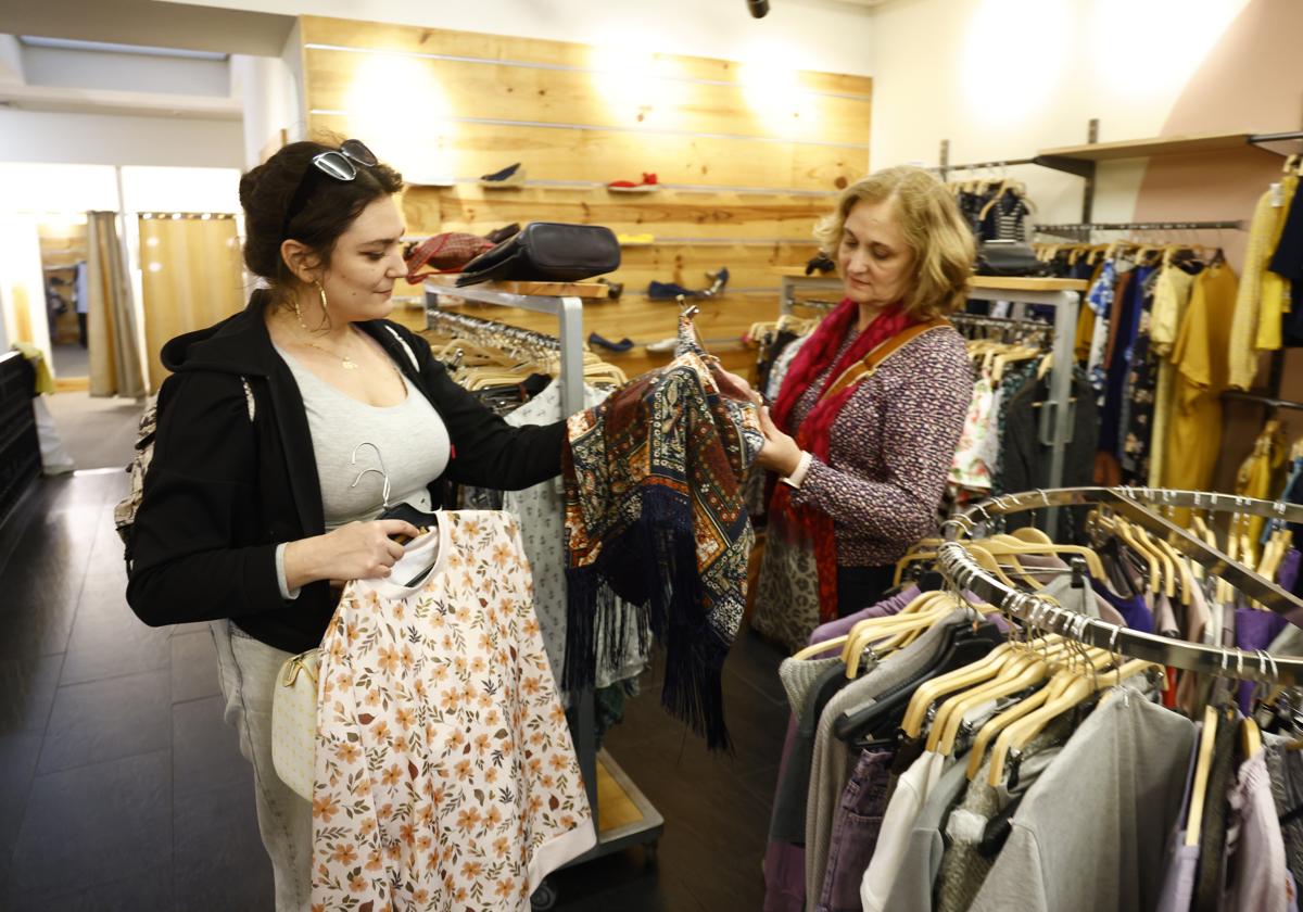 Lucía y Paloma ojean varias prendas de ropa en la tienda Koopera de la calle Postas